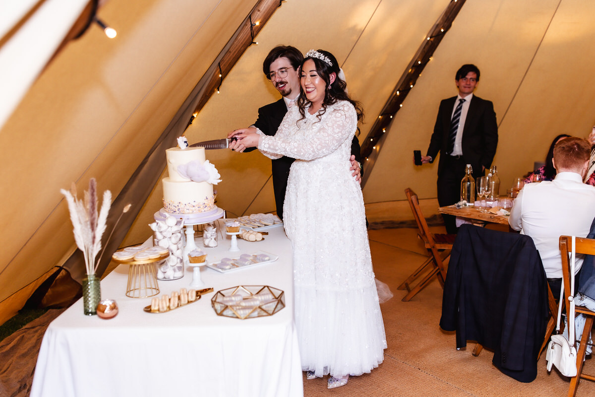 bride and groom cutting their wedding cake at outdoor wedding reception