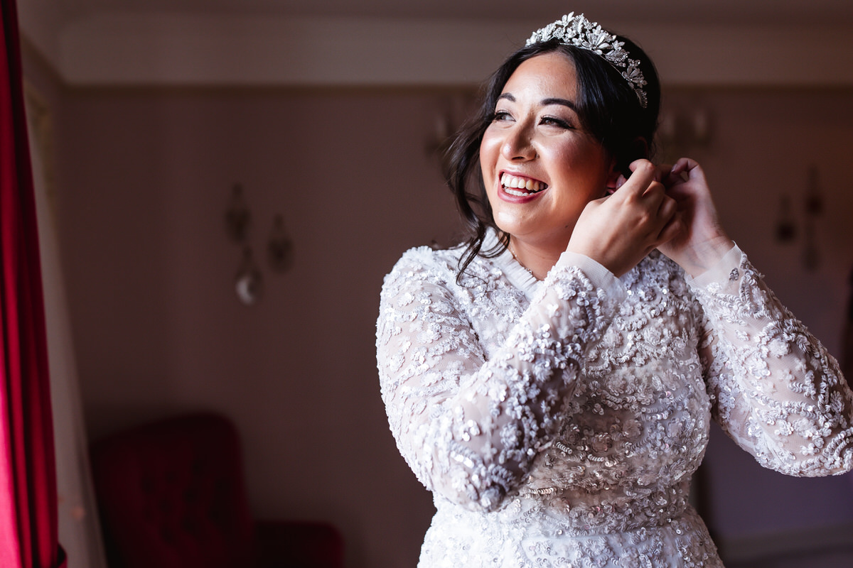 bride is putting her earrings on and getting ready