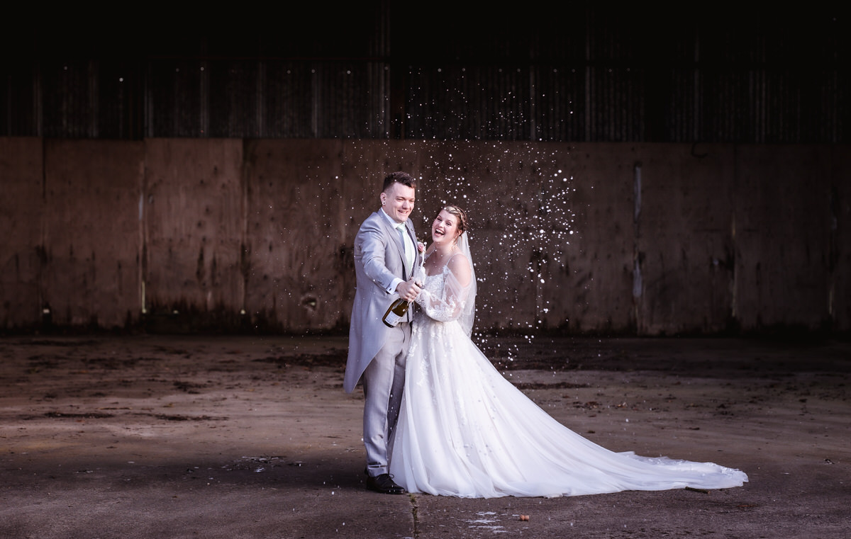 fun photo of Bride and groom opening champagne prosecco bottle bubbles photo