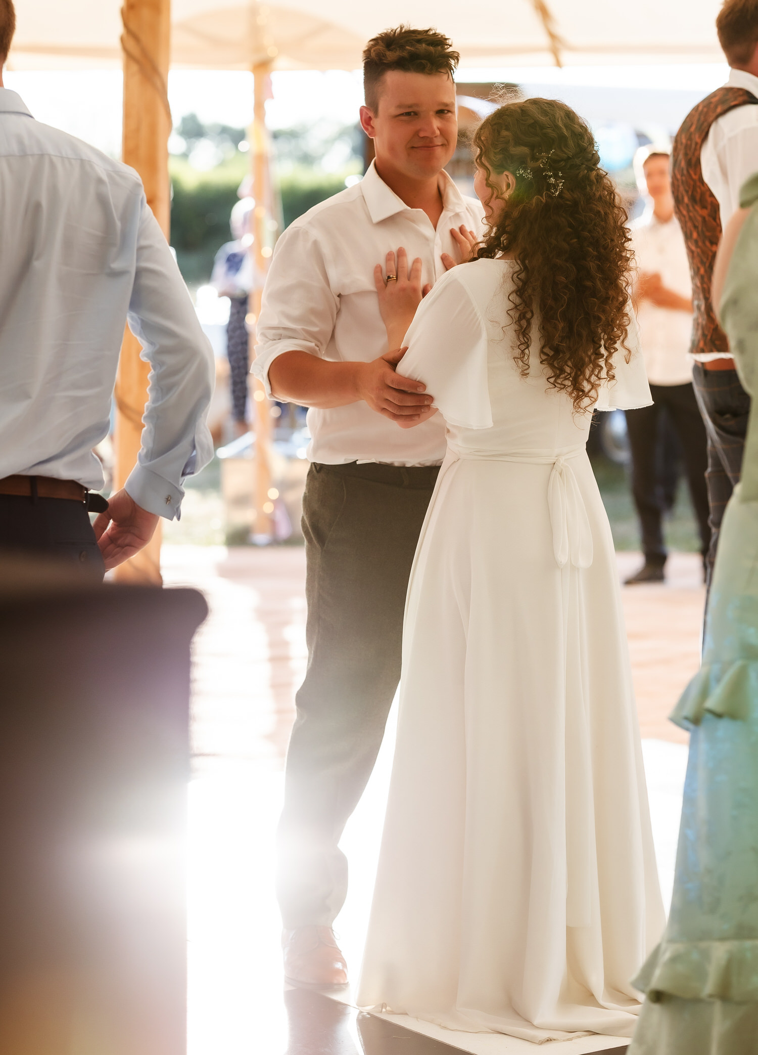 A bride and groom share a first dance at their wedding, gazing at each other and smiling. Sunlight streams onto the dance floor, creating a warm, romantic atmosphere—all beautifully captured by a country-house wedding photographer.